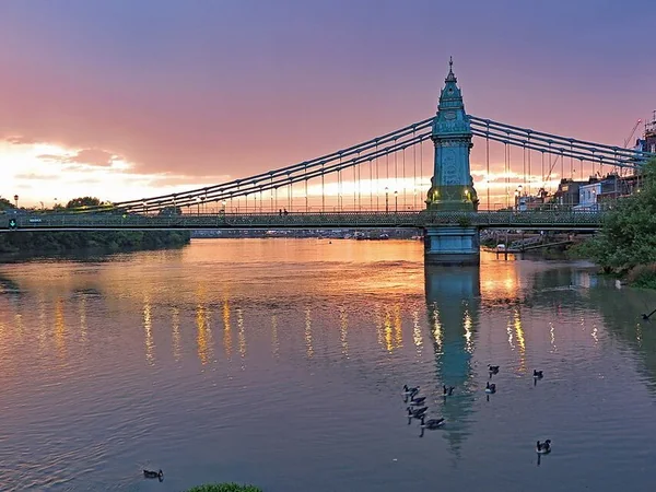 Hammersmith Bridge reflected in the Thames at sunset