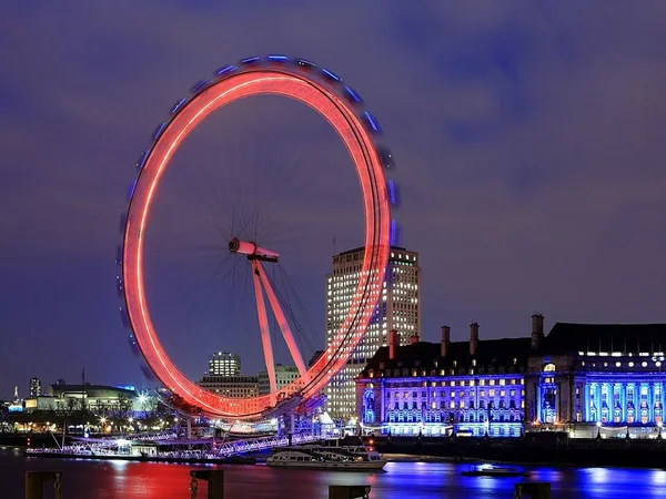 The illuminated London Eye and County Hall beside the Thames at night